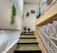 Interior of a family house with a staircase, railing, and decorative curtains.