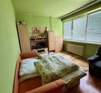 A room in a family house with a bed, a wardrobe, and a floor with a wooden decor.