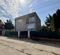 A family house in Tešedíkovo, surrounded by greenery, under a serenely blue sky.