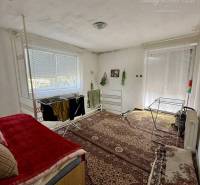 A room in a family house with a carpeted floor, a bed, and a clothes drying rack.