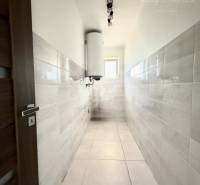 A hallway with white tiles and doors with a wooden design in a family house.