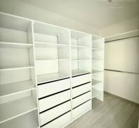 A wardrobe in a family house with white shelves and a wooden decor floor.