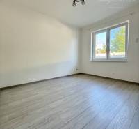 A room with a wooden decor floor and a window in a family house.
