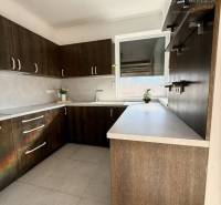A kitchen in a family house with dark cabinets and large windows.