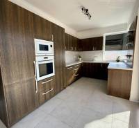 A kitchen with dark cabinets and a light floor in a family house.