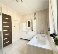 A bathroom in a family house with a bathtub and ceramic tiles.