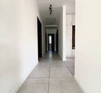 A hallway with white walls and light tiles in a family house.