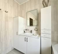 Bathroom in a family house with light furniture and a mirror.