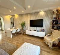 Living room of a 4-room apartment with a sofa, a desk, and shelves with books.