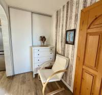 Interior of a 4-room apartment with an armchair, wooden flooring, and modern storage space.