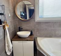 A bathroom in a 4-room apartment with a sink, mirror, and bathtub, decorations on the shelf.