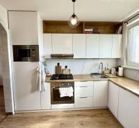 Kitchen in a 4-room apartment with wooden flooring, a light fixture, and built-in appliances.