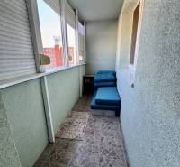 A balcony of a 4-room apartment with tiles and sliding windows in a housing estate.