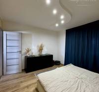 A bedroom in a 4-room apartment with light wooden furniture and curtains.