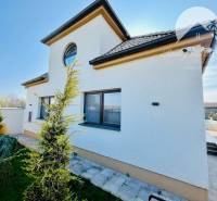 A family house with a side view, a landscaped front garden, and a paved area in the yard.