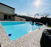 Family house with a pool, stone terrace, and a sunny day in the garden.