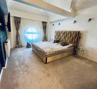 A bedroom in a family house with lighting effects, a couch, and a comfortable bed.