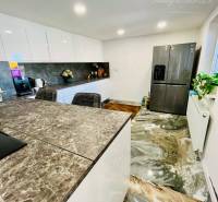 A kitchen in a family house with a marble floor, a bar counter, and a modern kitchen unit.