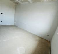 A room in a 3-room apartment with white walls and prepared ceiling wiring.