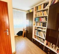 A room with bookshelves, a floor with a wooden decor, a door to the room.