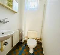 A bathroom in a family house with colorful tiles, a sink, and a toilet.