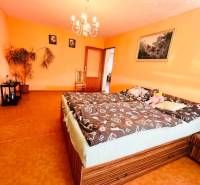 A room in a family house with orange walls, a wood-patterned floor, and a chandelier.
