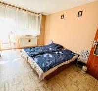 Bedroom in a family house with a bed and a large window, floor with wood decor.