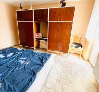 A bedroom in a family house with a large wardrobe and patterned floor.