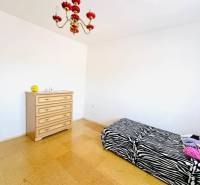 Interior of a family house with a bed, dresser, and chandelier, floor with wood decor.