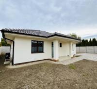 A family house in Topoľníky with a sloped roof and a paved walkway in the yard.