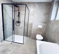 A family house bathroom with large-format tiles, a shower corner, and a bathtub.