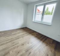 White room with wood-patterned flooring in a family house.