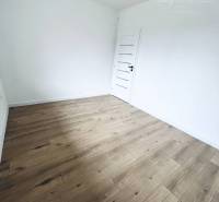 A room in a family house with white walls and a wooden decor floor.