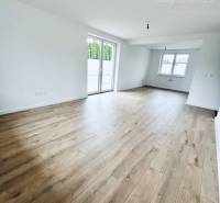 Living room in a family house with wood-patterned flooring and large windows.