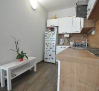 A kitchen in a 2-room apartment with a wooden decor floor and white furniture.
