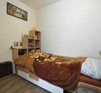 Simple bedroom with a bed, shelves, and decorations in a 2-room apartment.