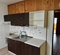 A kitchen in a 4-room apartment with white and dark cabinets, and a floor with a wood decor.