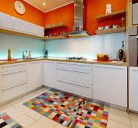 A kitchen in a 2-room apartment with a colorful rug and modern equipment.