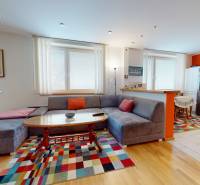 A spacious living room in a 2-room apartment with a colorful carpet and a wooden decor floor.