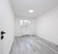 A room with white walls and a wooden decor floor in a 3-room apartment.