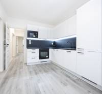 A kitchen in a 3-room apartment with a white cabinet and a floor with a wooden decor.