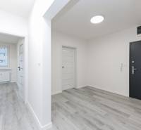 A hallway with light walls and a wooden decor floor in a 3-room apartment.