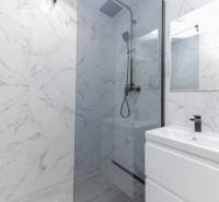 A bathroom in a 3-room apartment with a large mirror and a glass shower enclosure.