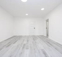 A spacious room with white walls and a wooden decor floor in a 3-room apartment.