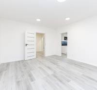 Interior of a 3-room apartment with white walls and a floor with a wood decor.
