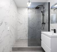 Bathroom with a shower, marble tiles, and a sink in a 3-room apartment.