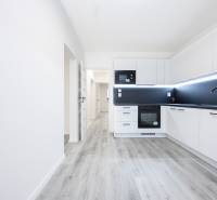 Kitchen in a 3-room apartment with white cabinets and a wood-patterned floor.