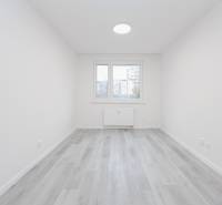 A bright room with a wooden decor floor in a 3-room apartment, window, and radiator.