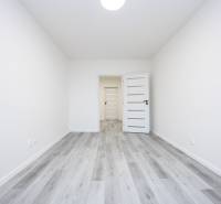 An empty room with wood-patterned flooring, white walls, and a door with narrow glass strips.