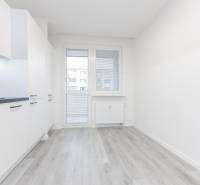 A kitchen in a 3-room apartment with white cabinets and a wood-patterned floor.
